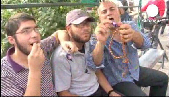 Men in Gaza celebrate with sweetcakes upon hearing news of bus bombing in Tel Aviv