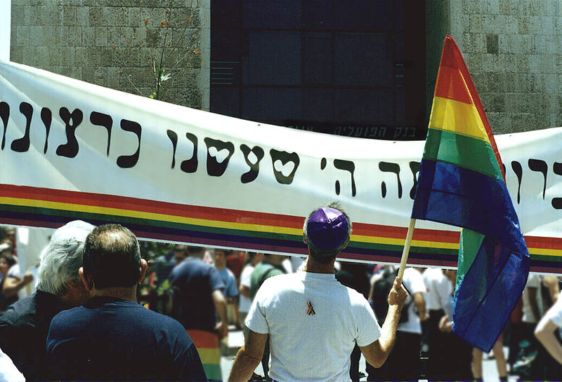 Scene from the first Pride Parade in Jerusalem in 2002. The banner translates to "Blessed are You, God, Who made us according to your will," adapted from the blessing women traditionally recite each morning instead of the "Blessed are You, God, Who has not made me a woman" recited by men.  | CC via Wikimedia Commons