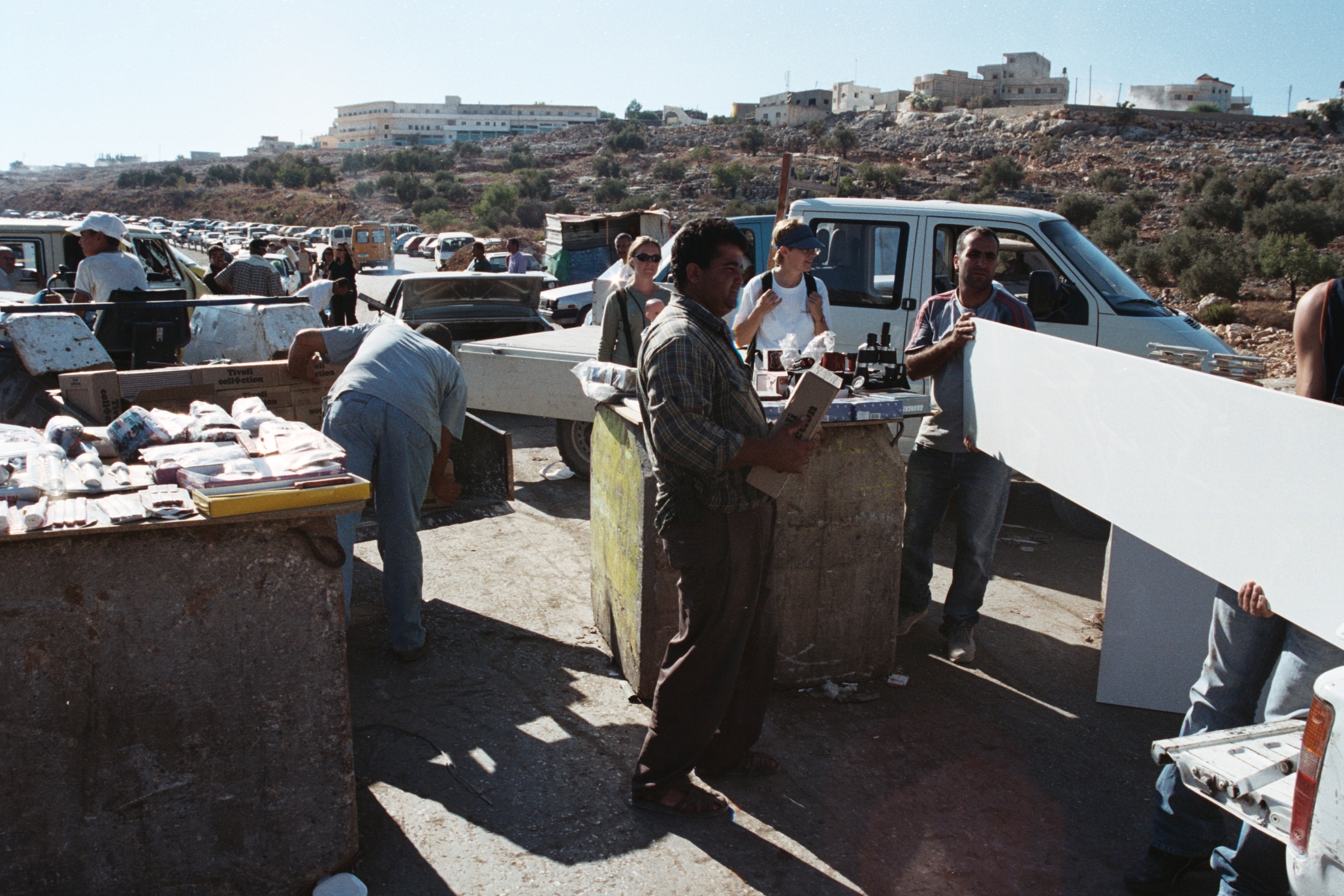 Palestinians unloading construction material from one truck to another in order to cross an Israeli unmanned roadblock between Palestinian cities in occupied West Bank. | By Czech160 [Public domain], via Wikimedia Commons.
