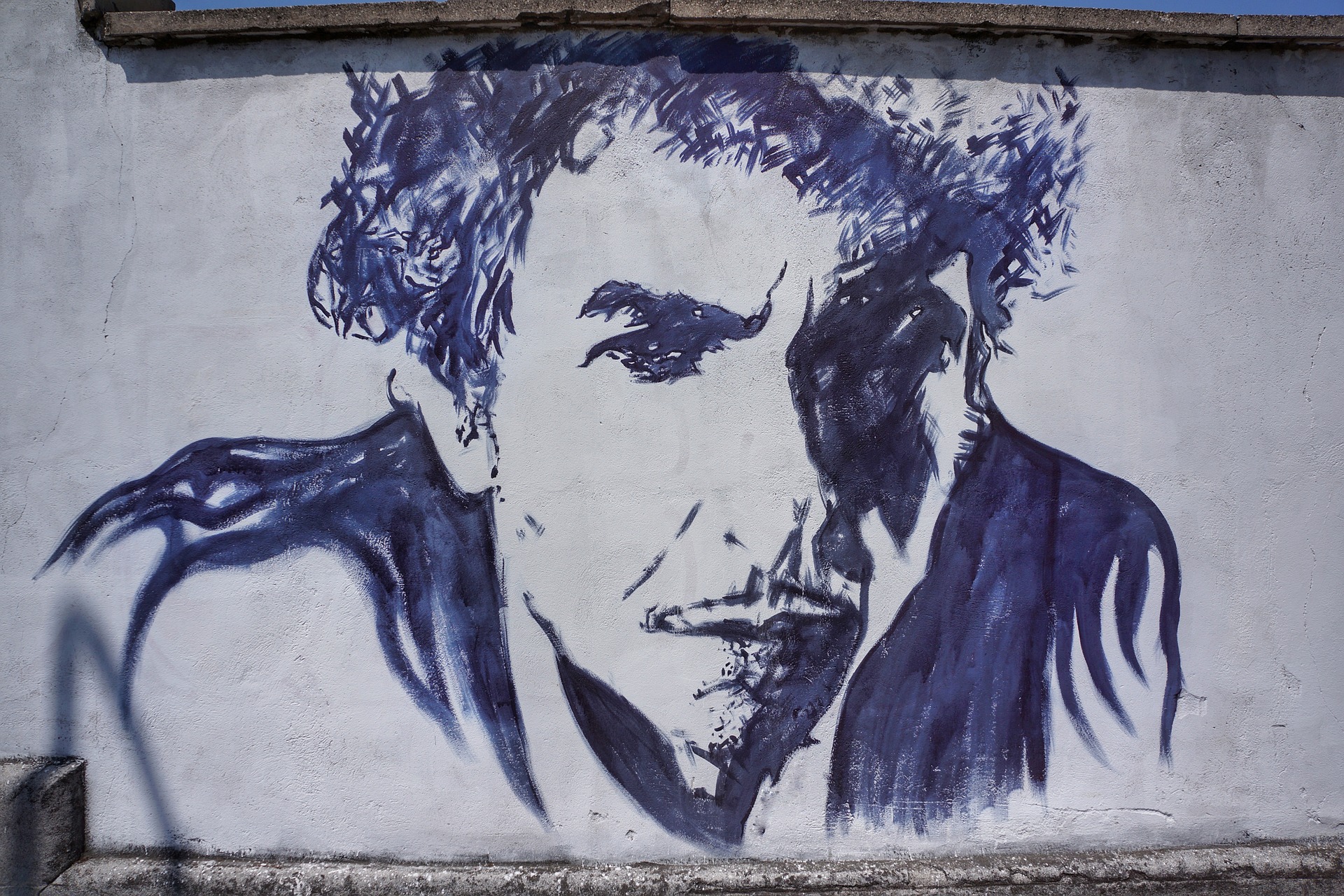 Image of a blue and grey mural of the musician Bob Dylan against a grey wall.